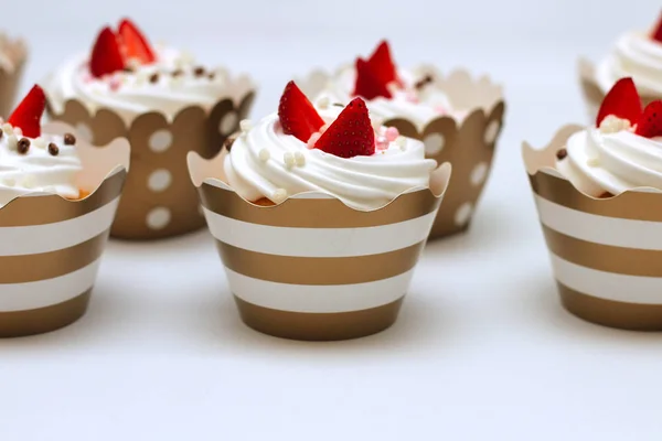 Těsné dortíky se šlehačkou na bílém podkladu zdobí čerstvé jahody a čokoládové kuličky. Izolovat — Stock fotografie
