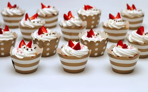 Närbild muffins med vispad ägg grädde dekorerad färsk jordgubb och chokladbollar på vit bakgrund. Isolera — Stockfoto
