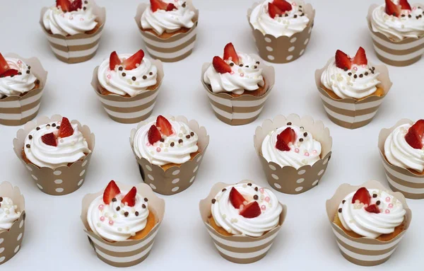 Närbild muffins med vispad ägg grädde dekorerad färsk jordgubb och chokladbollar på vit bakgrund. Isolerad vy uppifrån — Stockfoto