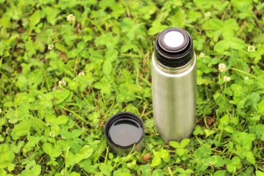 yeşil çim bir kapak ile metal termos