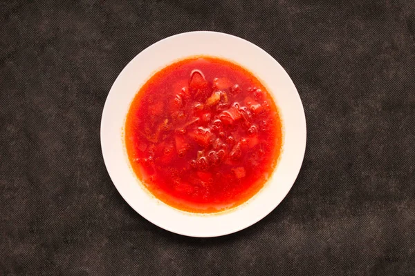 Vedere plat supă de sfeclă roșie de legume, pe masă. Borscht într-o placă albă pe pânză neagră . — Fotografie, imagine de stoc