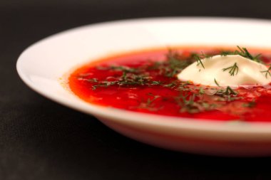 Ekşi krema ve koyu arka plan ile siyah tuval izole yeşillik ile pancar kökü çorba borscht Kase