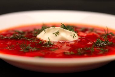 Ekşi krema ve koyu arka plan ile siyah tuval izole yeşillik ile pancar kökü çorba borscht Kase