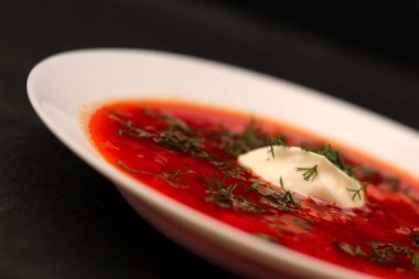 Ekşi krema ve koyu arka plan ile siyah tuval izole yeşillik ile pancar kökü çorba borscht Kase