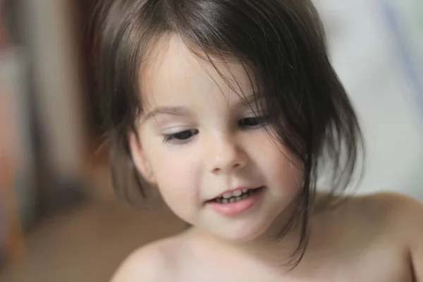 Retrato de uma linda menina sorridente com cabelos castanhos longos e olhar para baixo — Fotografia de Stock
