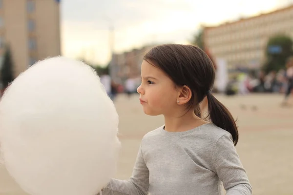 Pigtails ile küçük kız elinde bir şehir kutlamasında pamuk şeker büyük bir top tutar