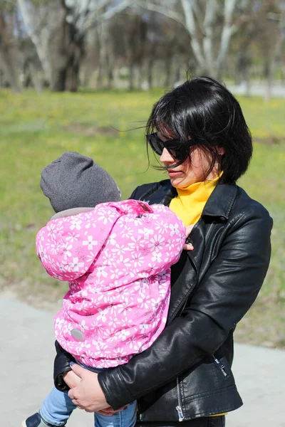 Mörkhårig Mor Med Glasögon Håller Sina Armar Ett Barn Som — Stockfoto