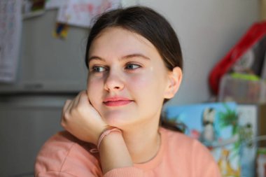 Kuyruğu olan genç bir kızın portresi mutfaktaki masada oturmuş gülümsüyor.