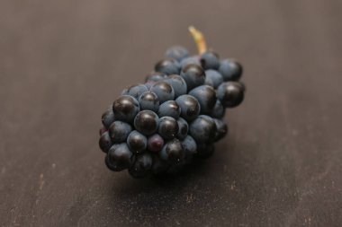 Bir demet taze toplanmış siyah üzüm. Koyu bir ahşap yüzeyde.