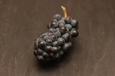 Ahşap kara yüzeyde yapayalnız olgun üzümler sürüsü