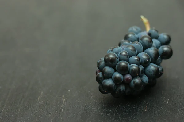 Kilka Świeżo Zebranych Czarnych Winogron Ciemnej Drewnianej Powierzchni — Zdjęcie stockowe