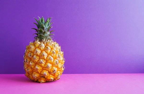 Pineapple fruit on violet purple background. Copy space.