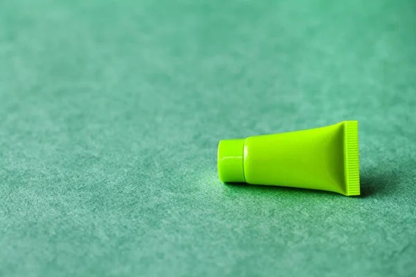 Blank green cosmetic tube on green background. Simple plastic container, mock up packaging design. shallow depth of field, copy space photography