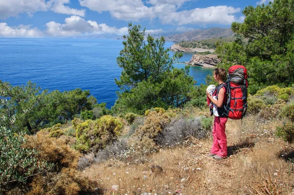 A woman with a baby in a sling and a large backpack travels along the Carian path. Turkey — Stock Photo, Image
