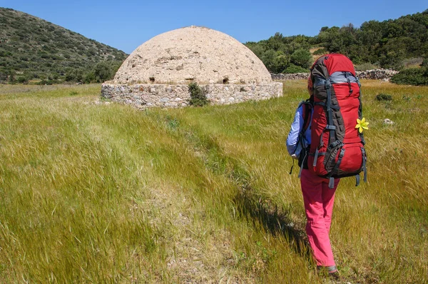 Woman with a large backpack goes to the old traditional antique tank with water. Turkey — Stock Photo, Image