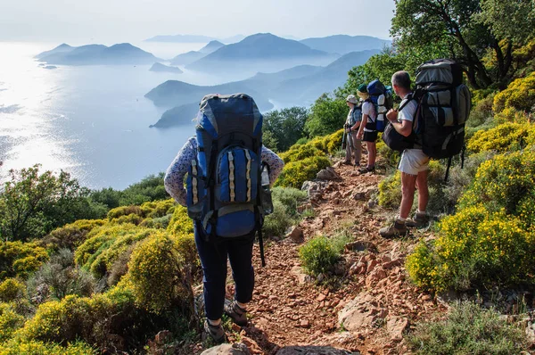 bir sırt çantası ile turist grup Akdeniz kıyısında duruyor ve mesafe içine görünüyor