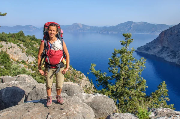 Mom with baby in a sling and a large backpack stands on top of the sea landscape. Turkey. Lycian Way — Stock Photo, Image