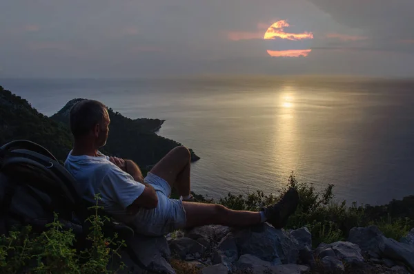 çok uzak bir ufuk batımını deniz kenarında sırt çantası ile seyahat
