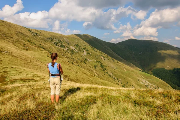 A girl with baby in a sling looks at the mountain range. Ukraine. Carpathian mountains — Stock Photo, Image