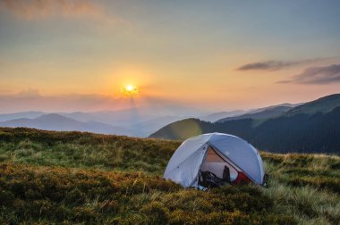 Karpatlar Ukrayna'da bir dağ silsilesi günbatımı zemin karşı çimenli yamaçta gri bir çadır