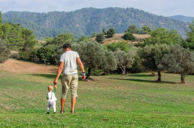 mutlu baba küçük çocukla bir Zeytin bahçesinde yürüyüş