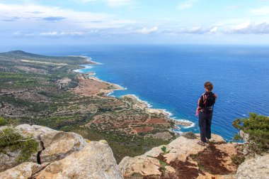 kayanın üzerinde duran ve Akdeniz denize bakarak askı içinde bebek ile anne