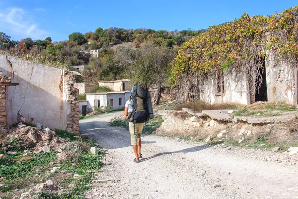 A man with large backpack walks through the ruins of an abandoned Turkish village in Cyprus — Stock Photo, Image