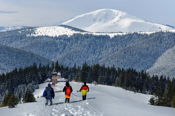 Drie toeristen in buiten kleren is rijden op houten Ski's in prachtige besneeuwde Karpaten. Oekraïne — Stockfoto