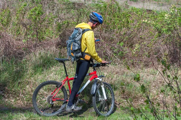 En man på mountainbike styrs i skogen våren med hjälp av en navigator — Stockfoto