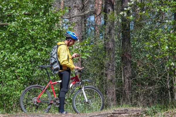 En man på mountainbike styrs i skogen våren med hjälp av en navigator — Stockfoto