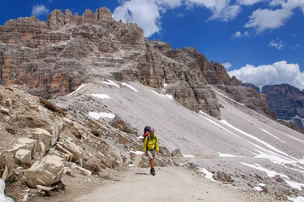 Papa avec un petit enfant dans un sac à dos marche le long de dolomites enneigées, Italie . — Photo