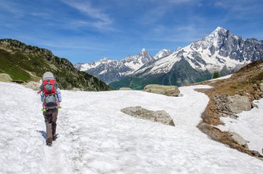 Bir sırt çantası küçük çocuk ile anne karla kaplı Dolomitler boyunca yürür, Italya.