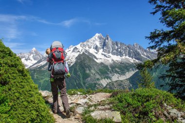 Bir sırt çantası küçük çocuk ile anne karla kaplı Dolomitler boyunca yürür, Italya.