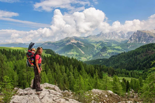 Mum with small child in a backpack walks along dolomites, Italy. Royalty Free Stock Photos