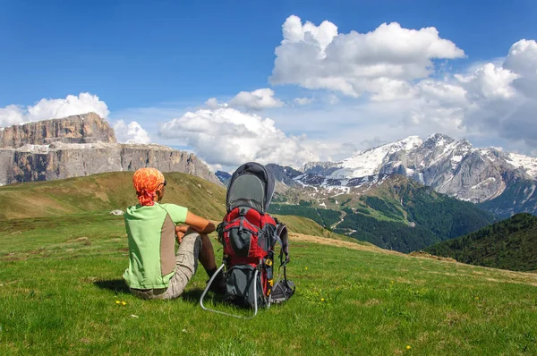 Young man sitting on a green lawn and looking a snow-covered dolomites, Italy. — Stock Photo, Image