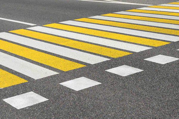 Асфальтированный дорожный переход с белыми и желтыми полосами разметки
