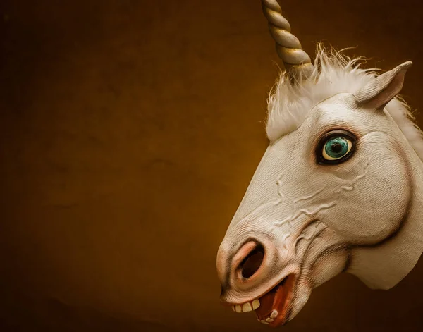 funny rubber unicorn mask on brown background
