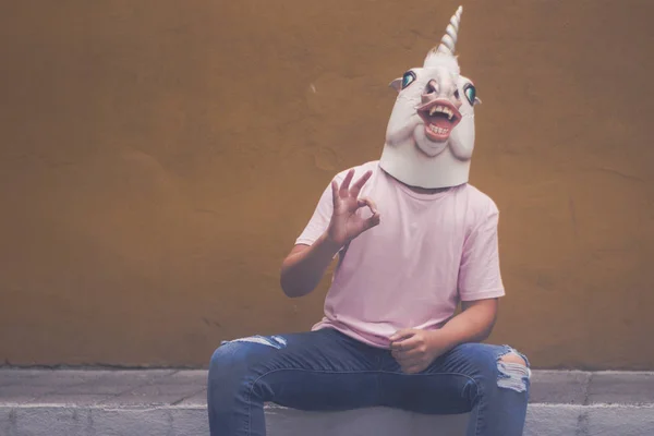 Young man in funny rubber unicorn mask