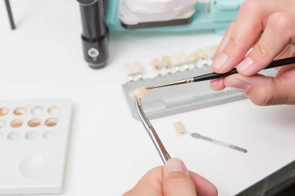 painting a tooth crown in dental laboratory