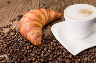 fincan Cappuccino ve ahşap masa üzerinde kahve çekirdekleri