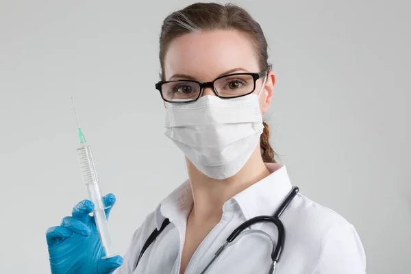 女性医生与注射器在她的手和听诊器和医疗面罩 — 图库照片