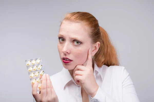 Mujer joven y preocupada con pastillas en la mano — Foto de Stock