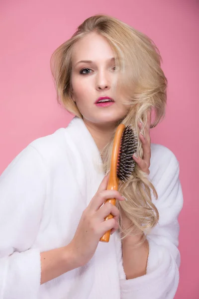 Mladá Blond Žena Kartáče Vlasy Před Růžové Pozadí — Stock fotografie