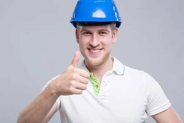 Young Smiling Worker Blue Hard Hat Shows Thumb — Stock Photo, Image