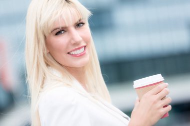 Genç sarışın iş kadını kağıt bardak kahve ile açık