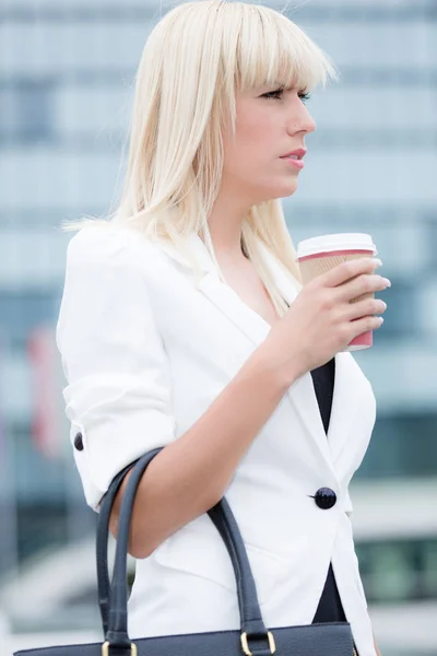 Young blonde business woman outdoor with a paper cup of coffee