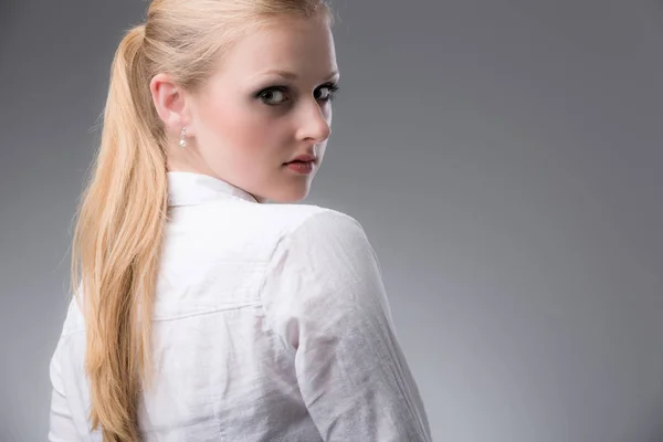 Guapa joven en una blusa blanca mira alrededor de su hombro — Foto de Stock
