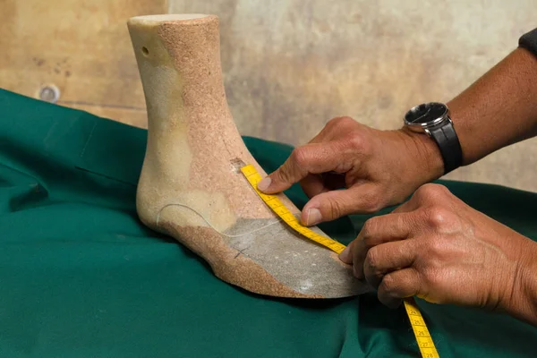 hands of a orthopedic shoemaker measuring an individual crafted