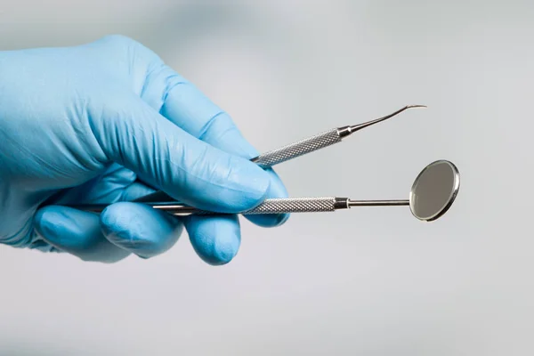 Dentist's hand in blue gloves with a set of dental instruments