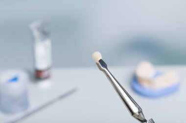 Diş laboratuarında yapay dişle cımbızı kapat.